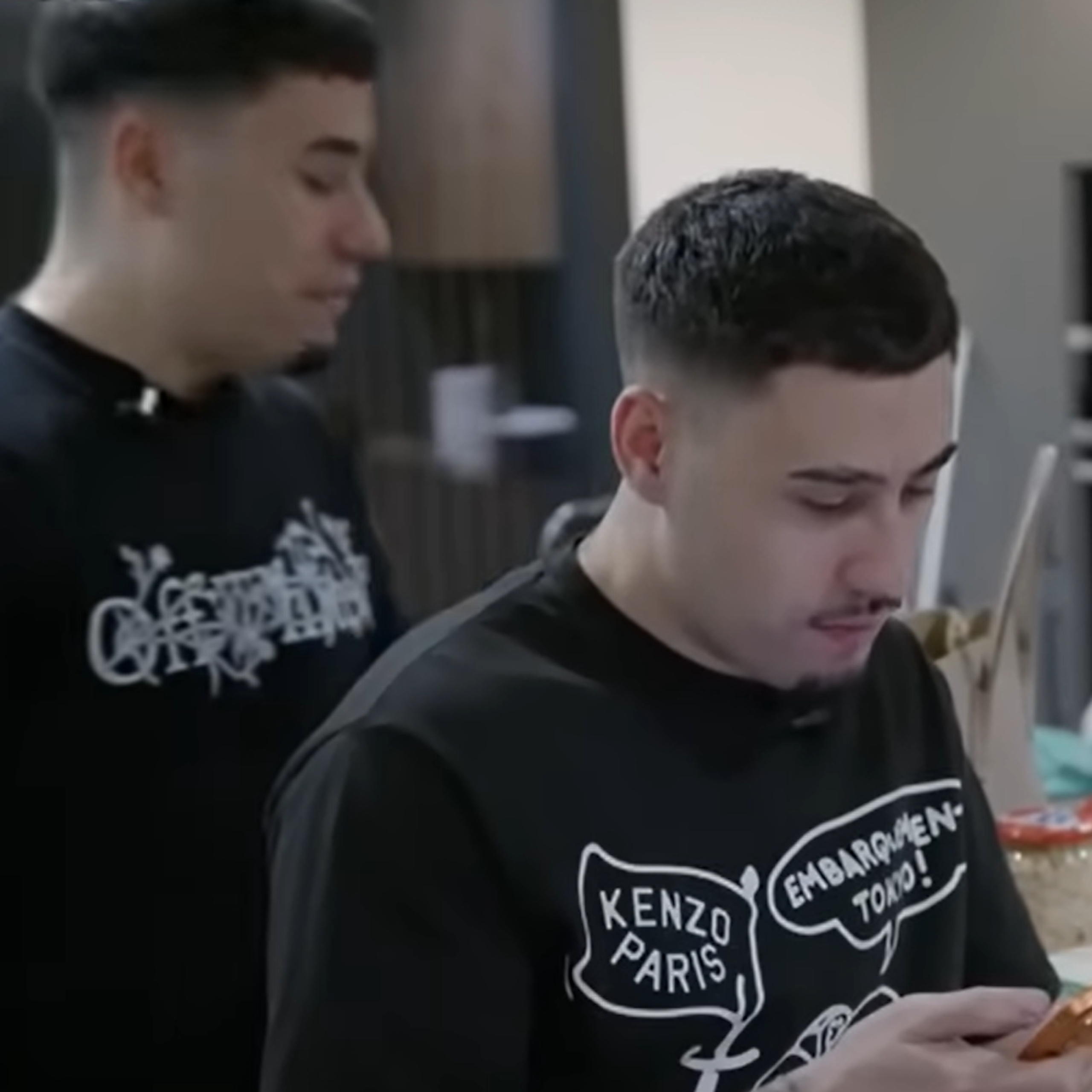 Imagen de dos gemelos, uno hablando con alguien y el otro mirando por el móvil.