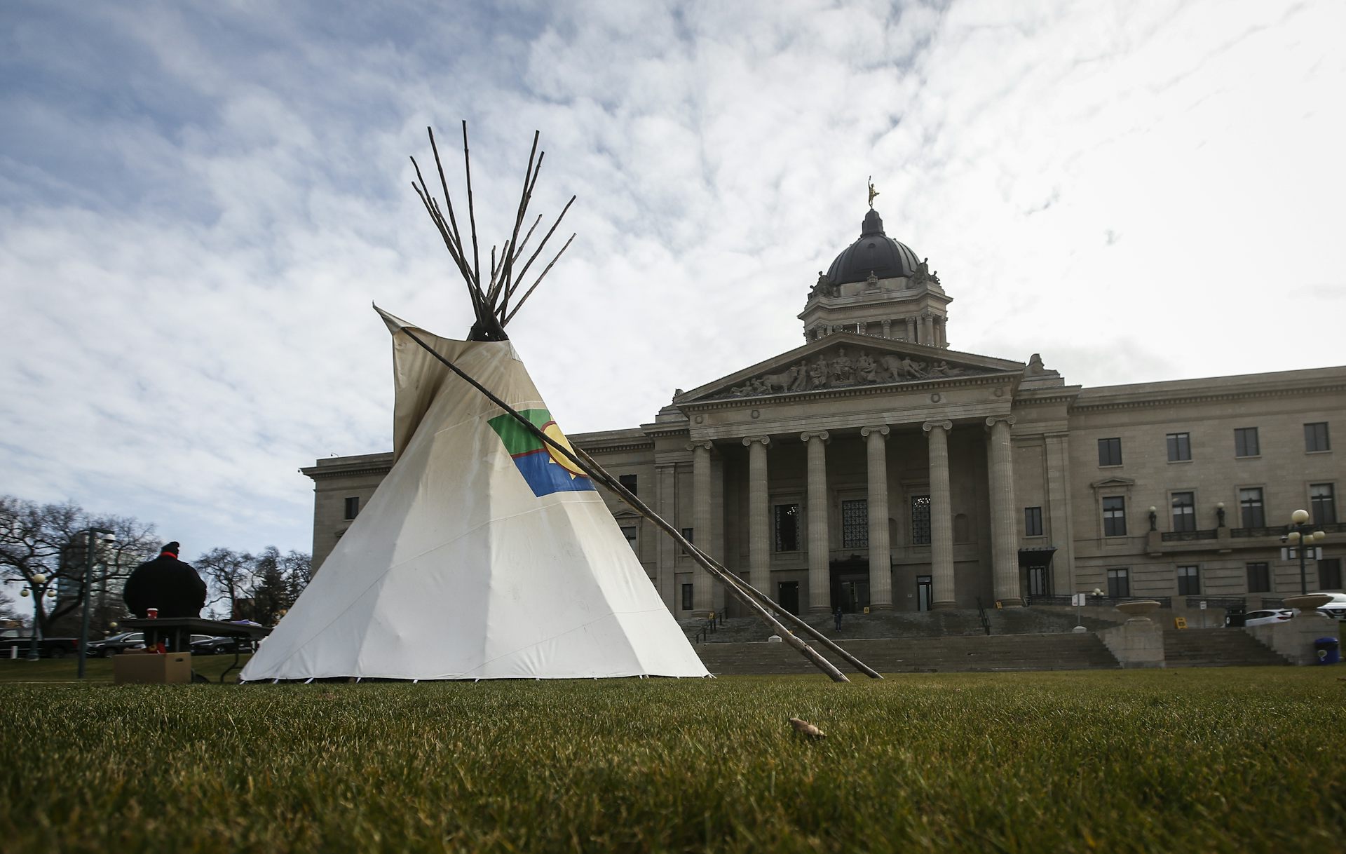 A teepee next to a legislature building.