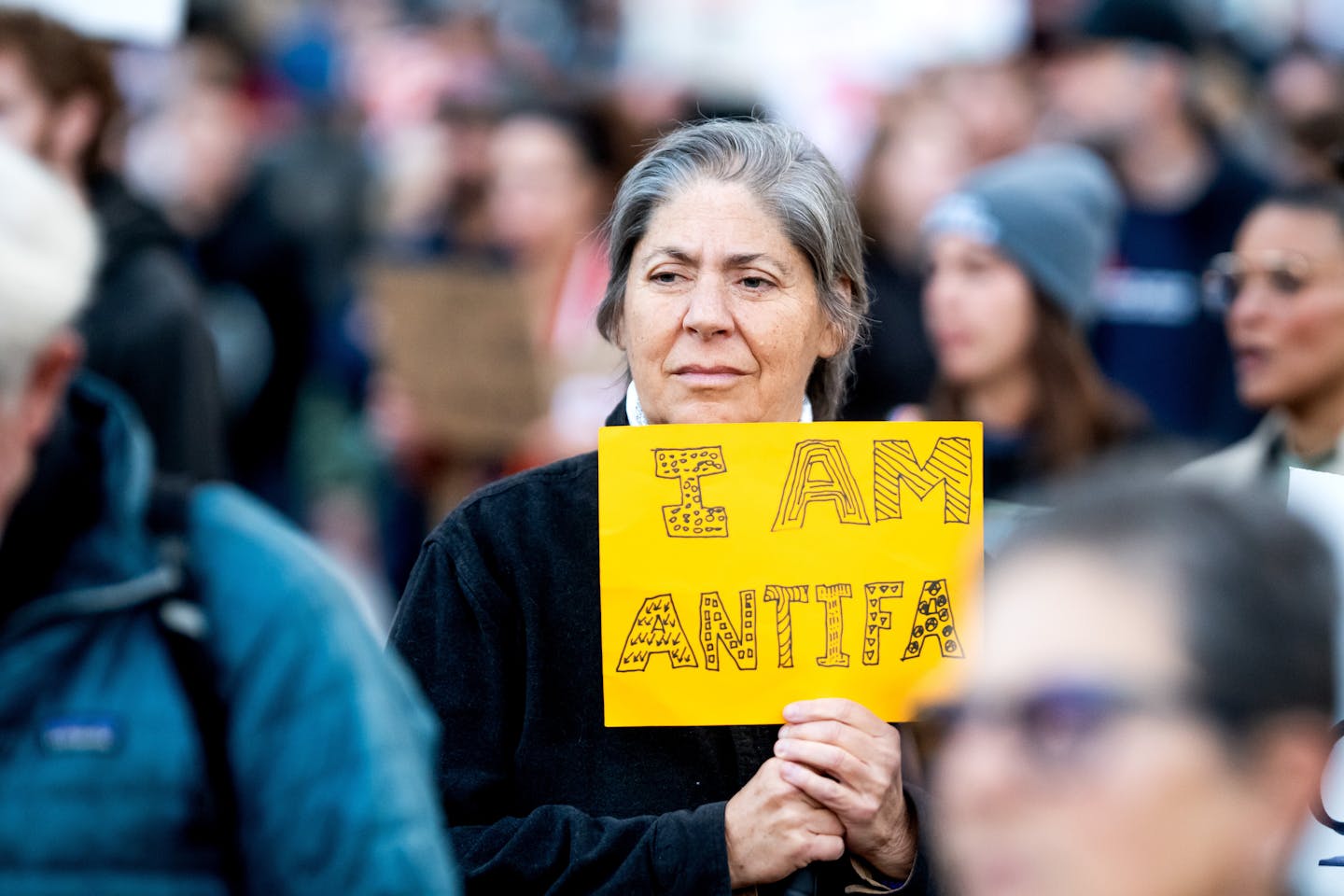 A woman holds a yellow sign while walking with a group of people.