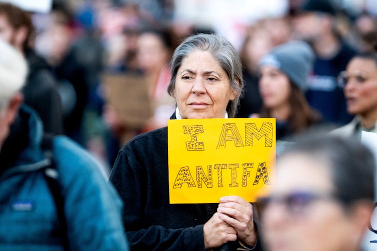 A woman holds a yellow sign while walking with a group of people.