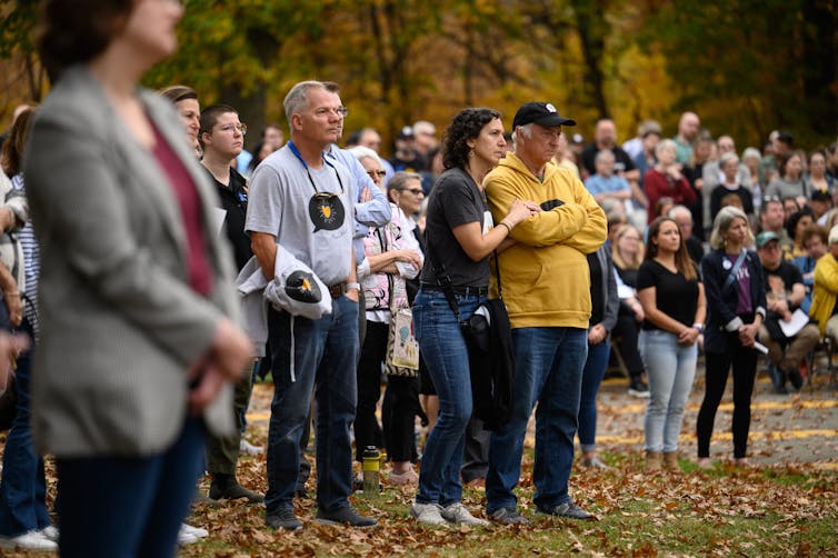 Dozens of people shown standing together outdoors