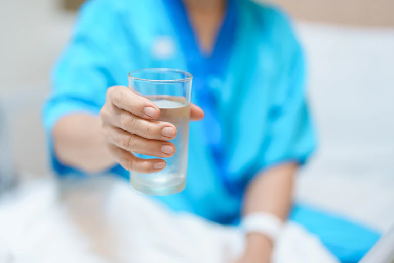 paciente hospitalar segurando um copo de água