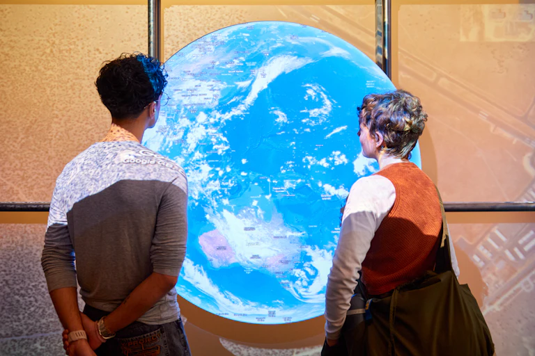 Two people looking at a large glowing globe