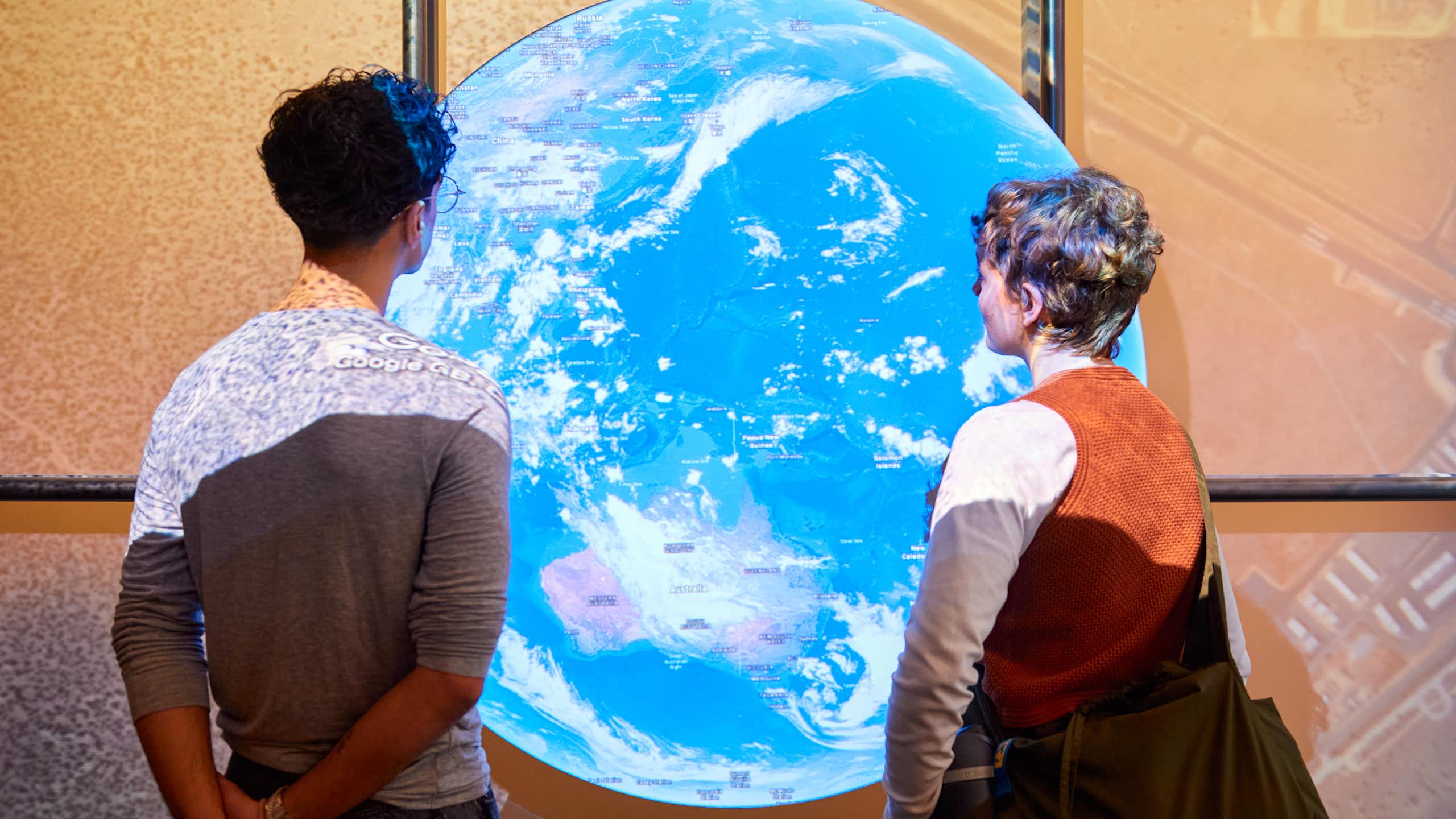 Two people looking at a large glowing globe