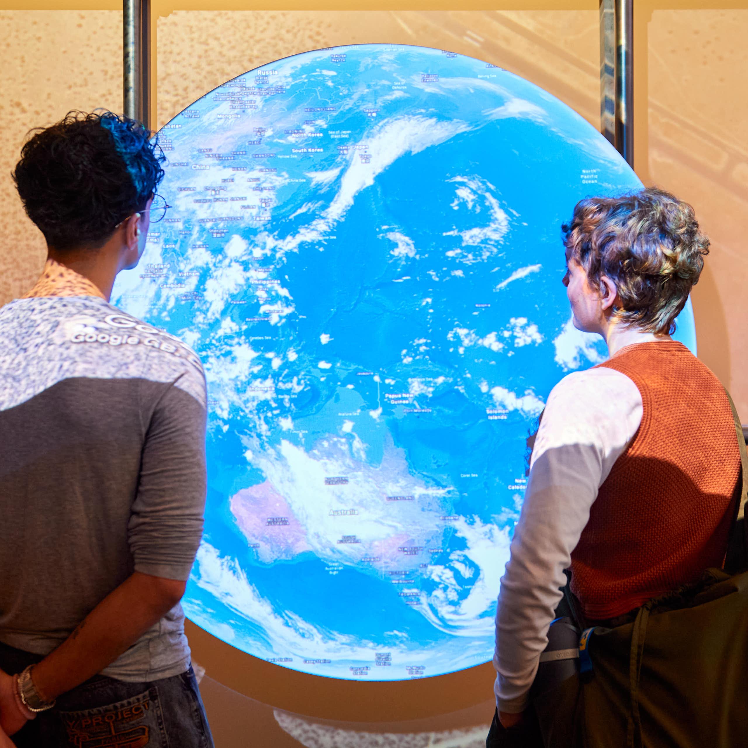 Two people looking at a large glowing globe