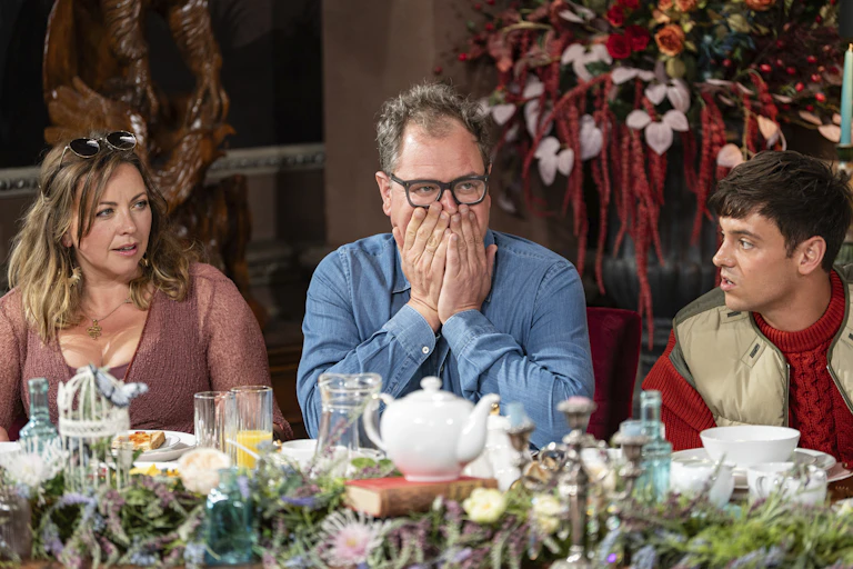 Comedian Alan Carr covers his mouth with his hands. He's flanked by singer Charlotte Church on the left and Olympian Tom Daley on the right.