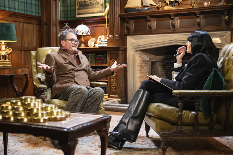 Alan Carr speaks to Claudia Winkelman on set of The Traitors.