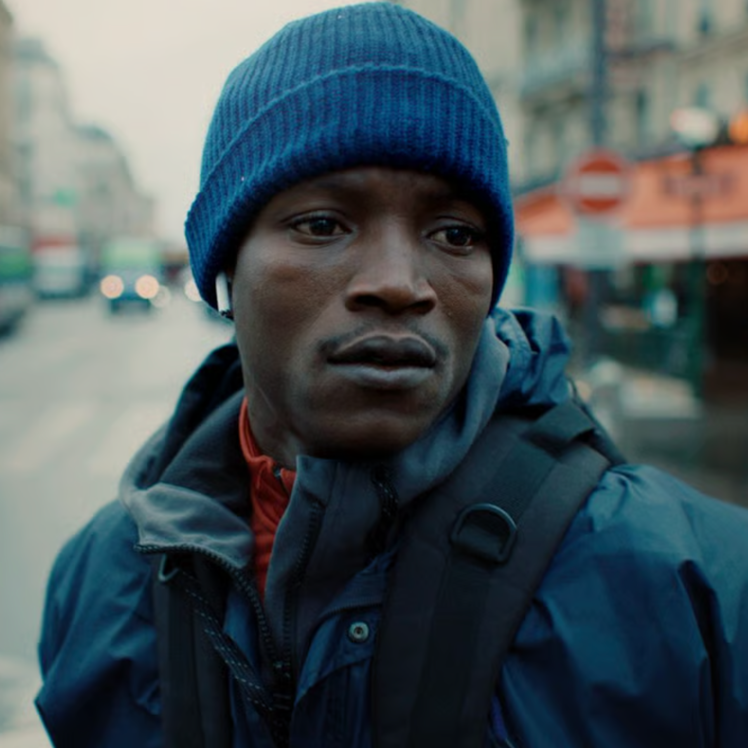 A young black man in a blue beanie looking sad.