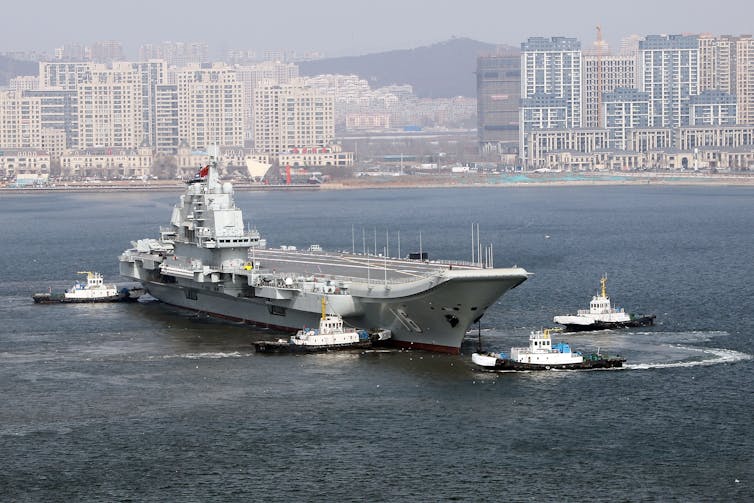 A large ship is seen in front of a city landscape.