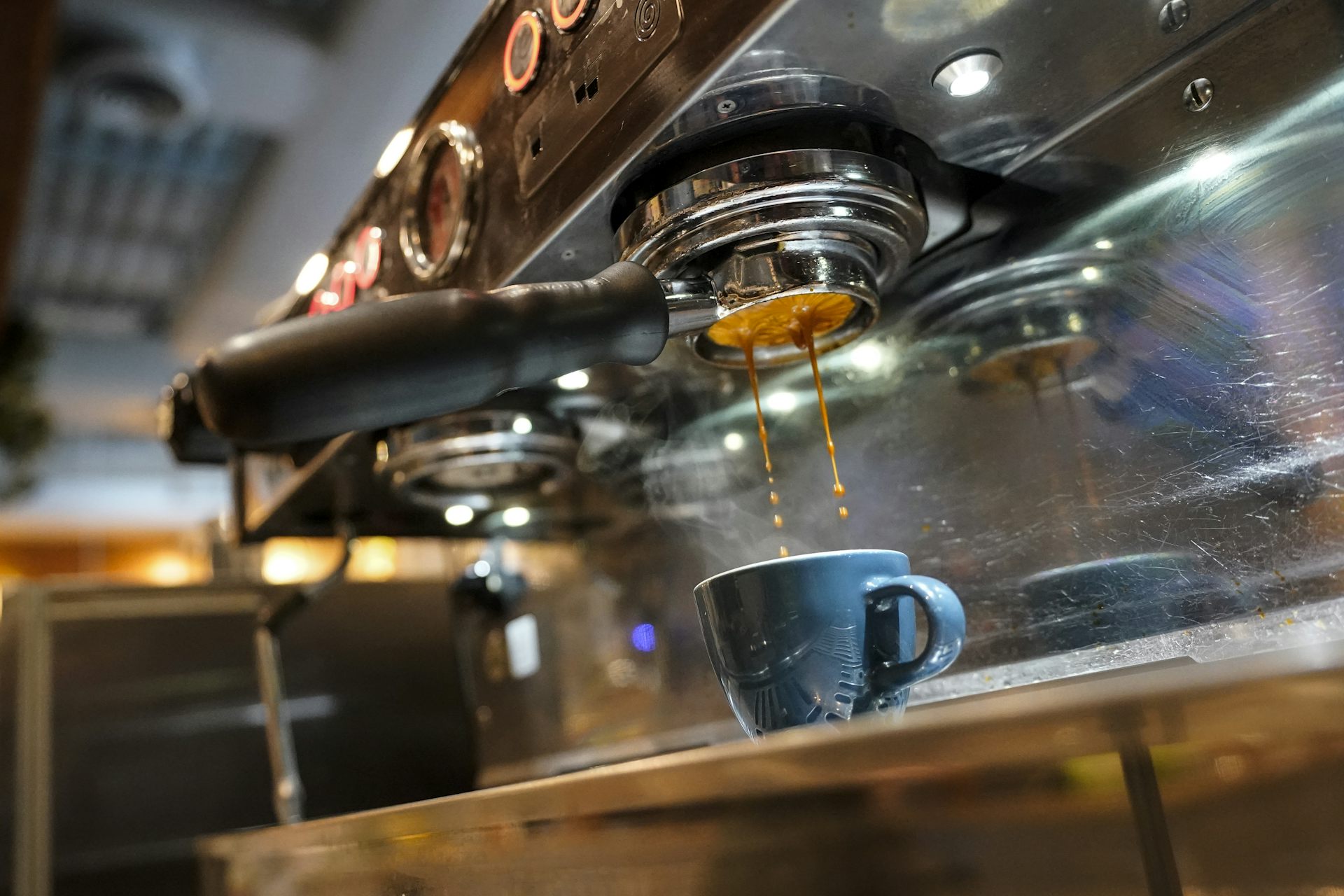 espresso falls from a coffee machine into a blue cup