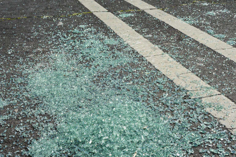 a large pile of shattered glass lying on a road.