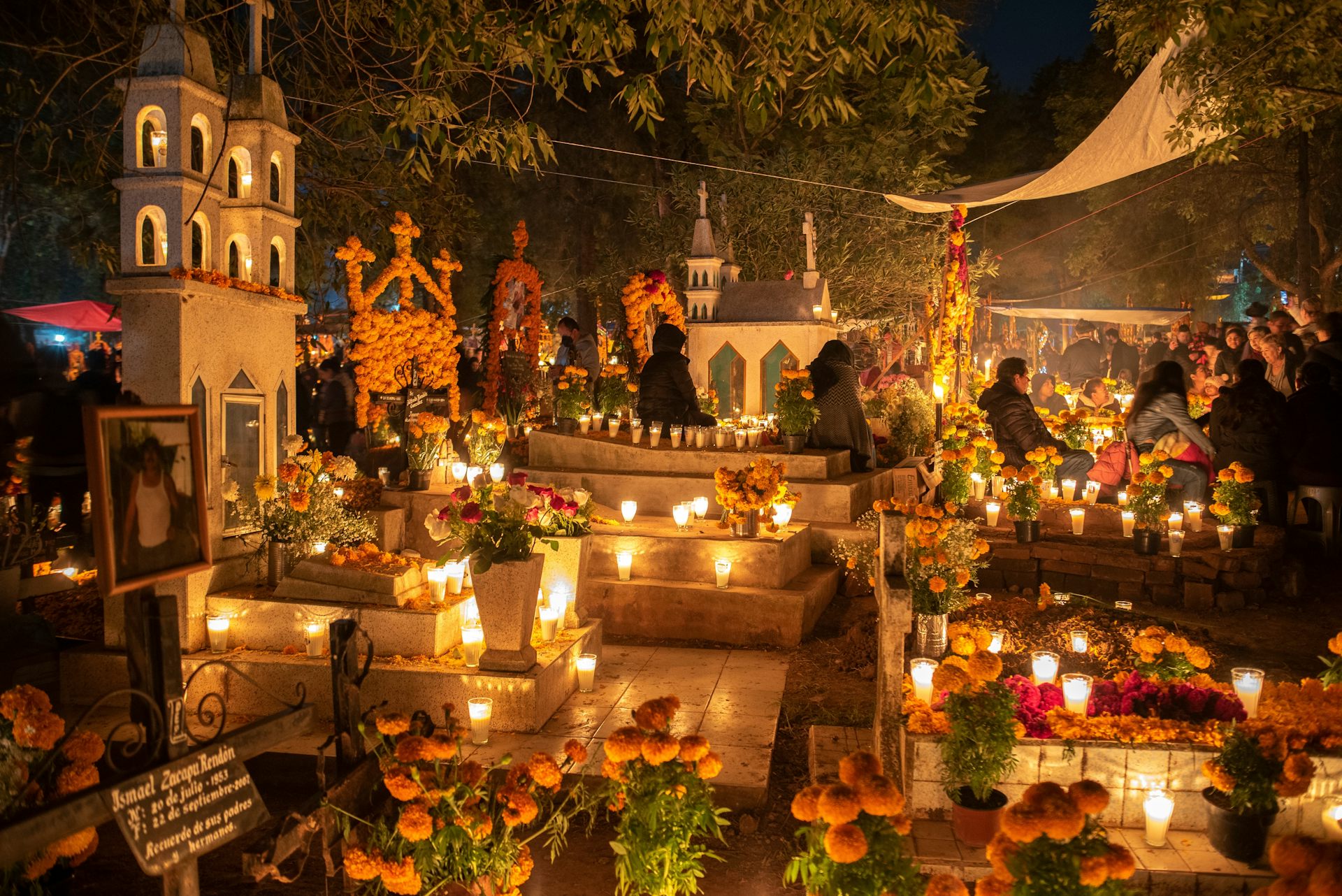 Un cementerio de noche con velas y adornos florales.
