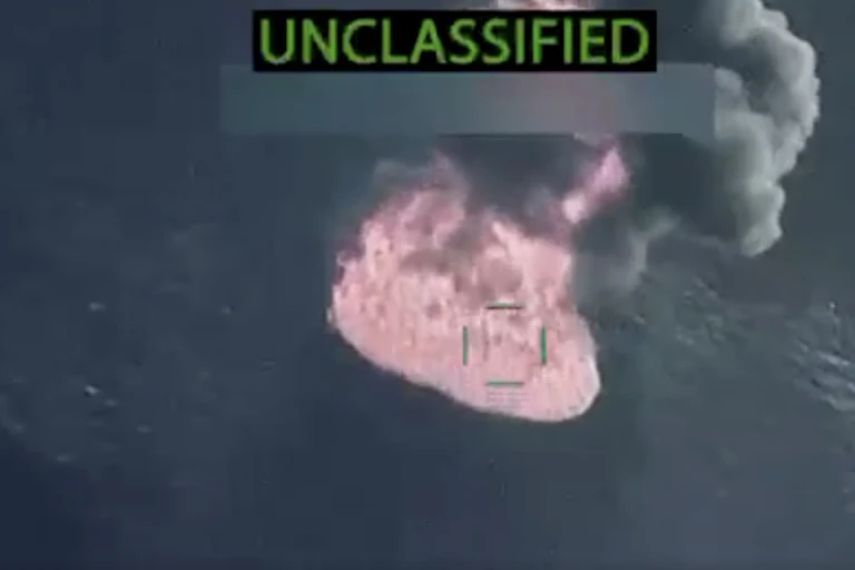 A burning boat in the middle of the water.