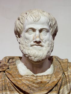 A white stone statue of a bearded man's head, with his shoulders wrapped in fabric folds.
