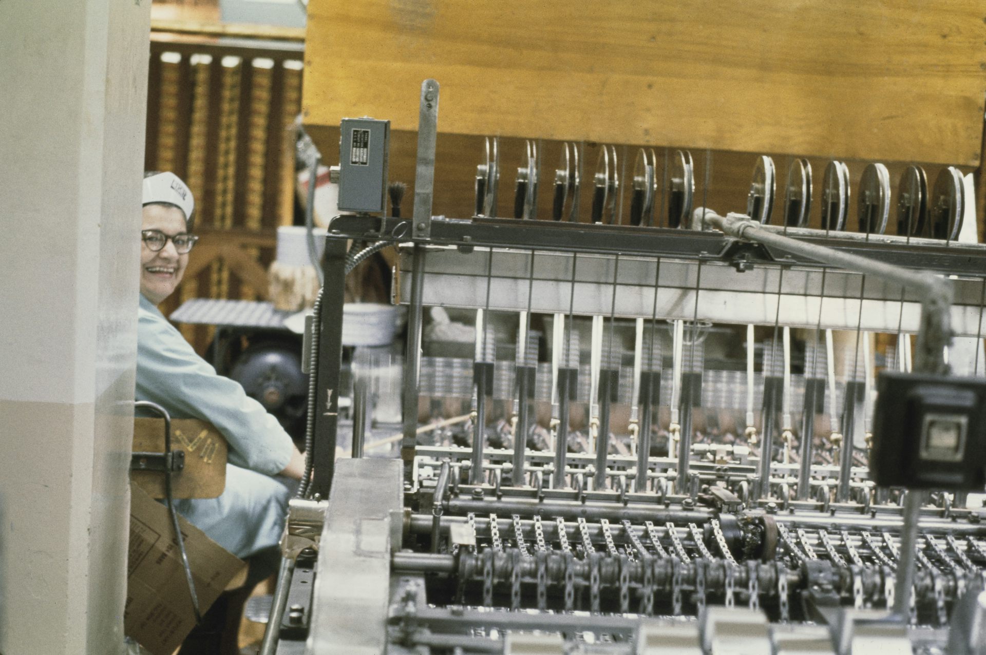 Sepia-toned photograph of woman working large machine in a factory
