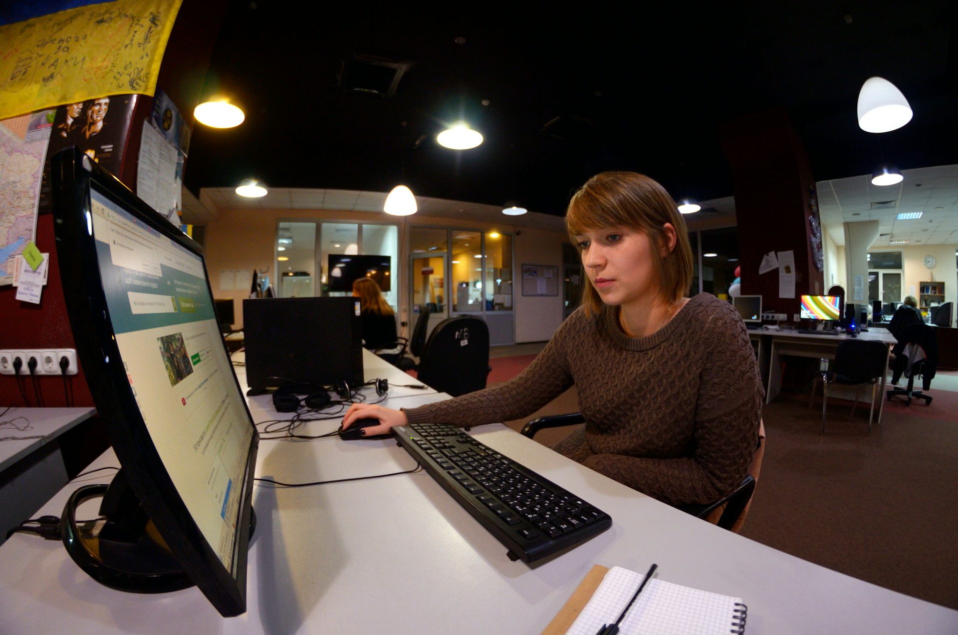 Una mujer trabaja con un ordenador en una redacción.