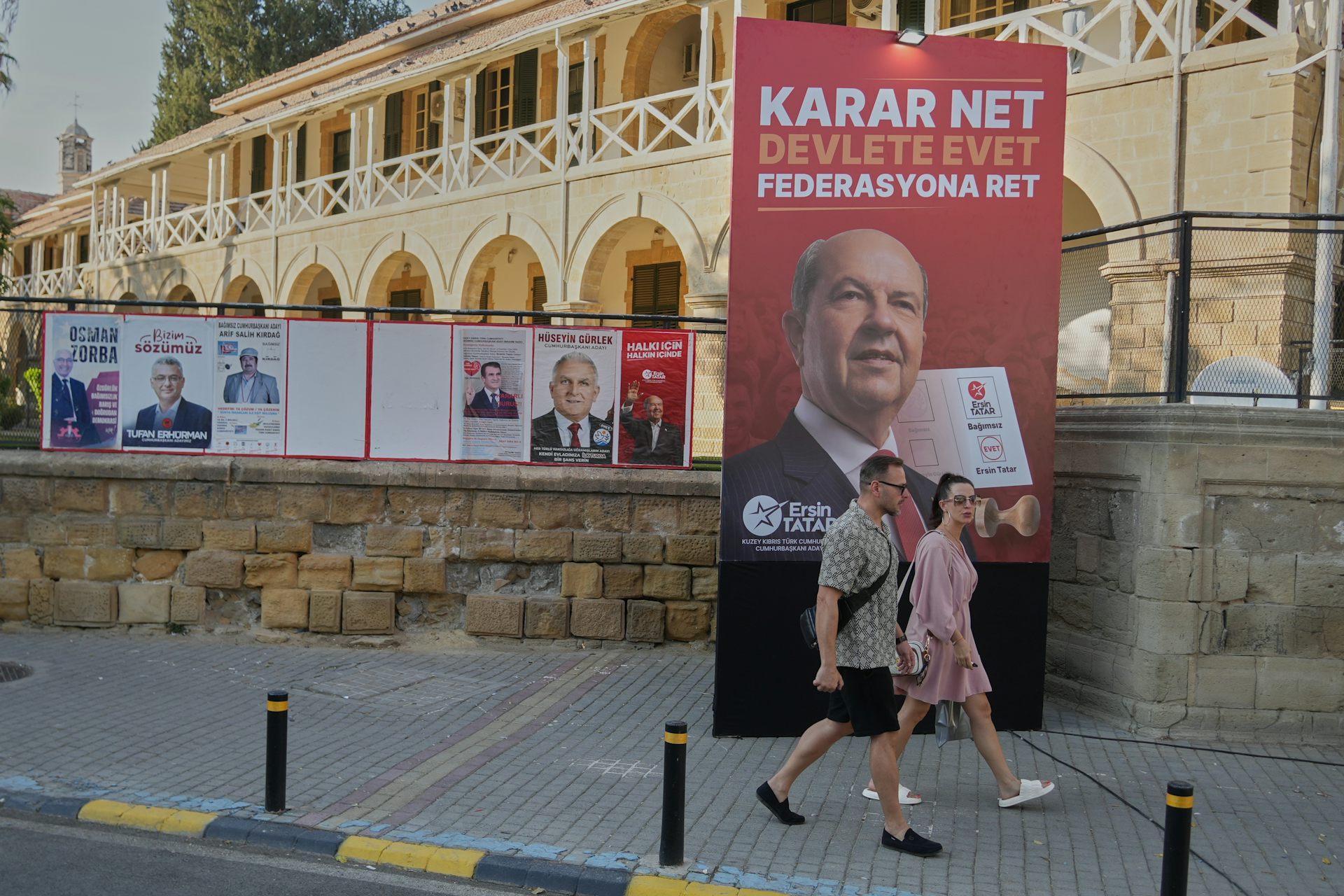 Dos personas pasan junto a carteles electorales en una calle de la ciudad.