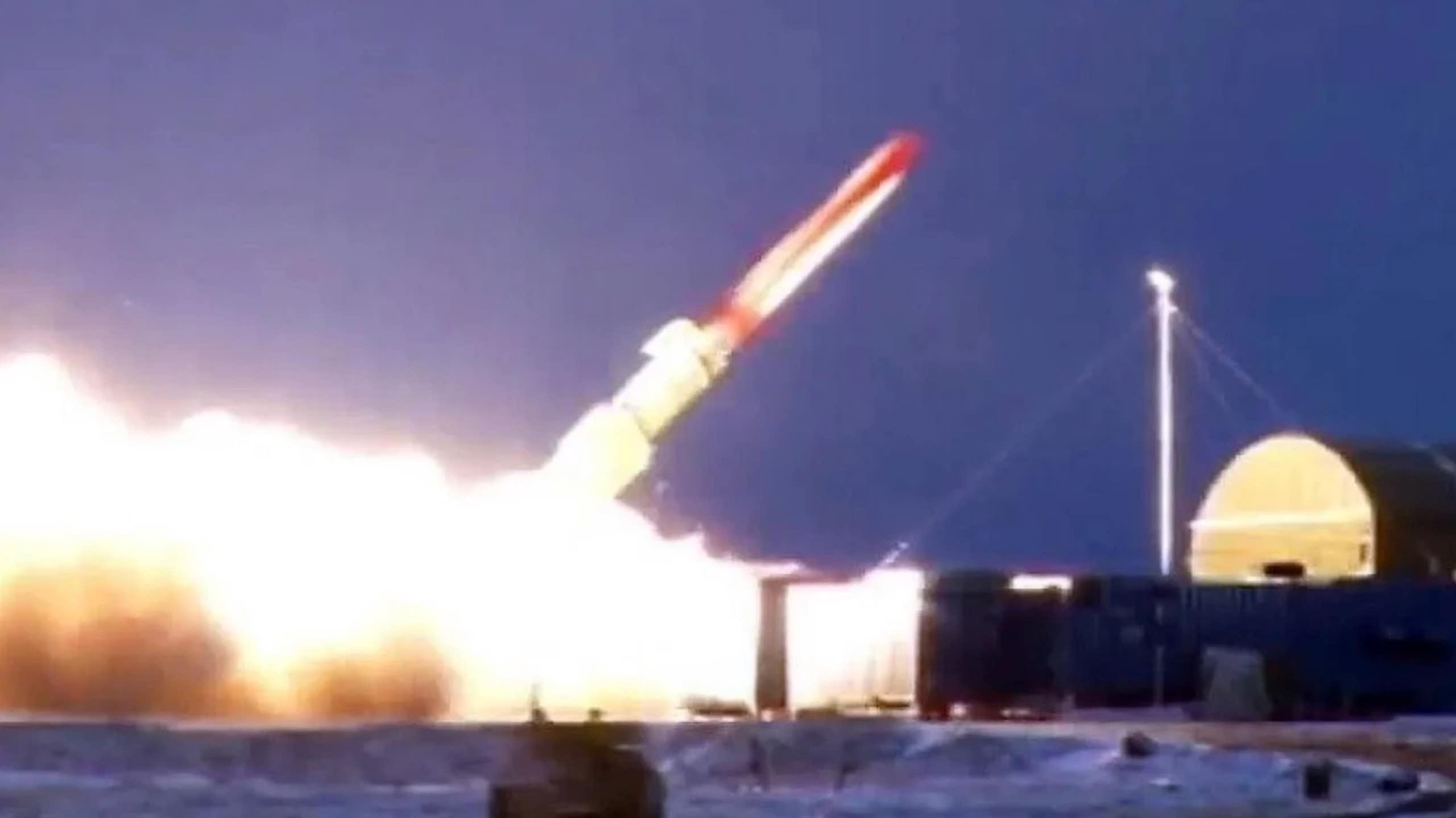 A red and white missile just above the ground at a 45 degree angle with flames at the bottom