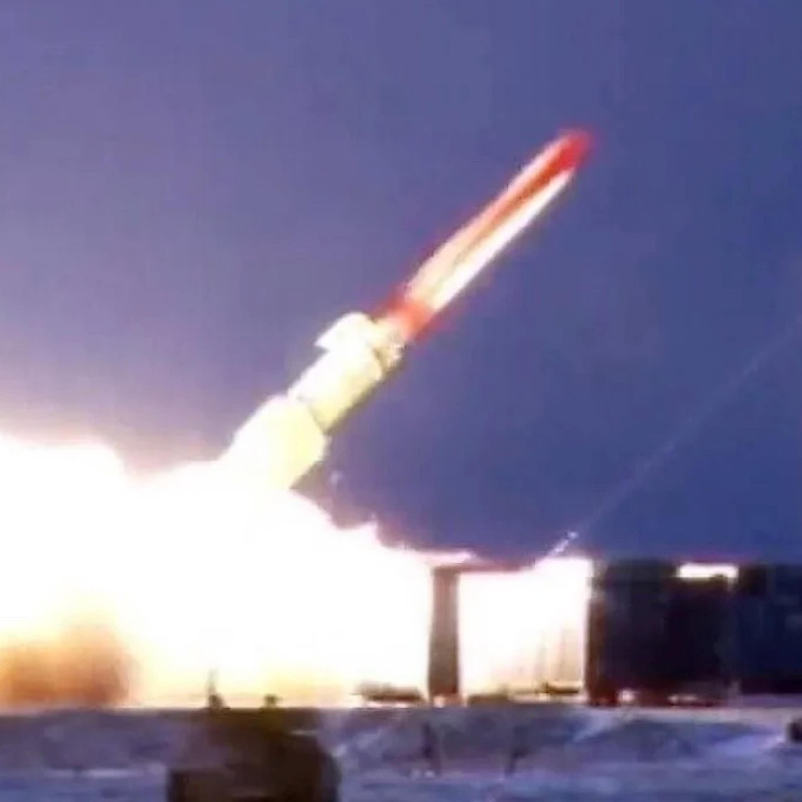 A red and white missile just above the ground at a 45 degree angle with flames at the bottom