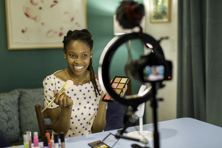 A young woman is seen filming a beauty and makeup vlog.