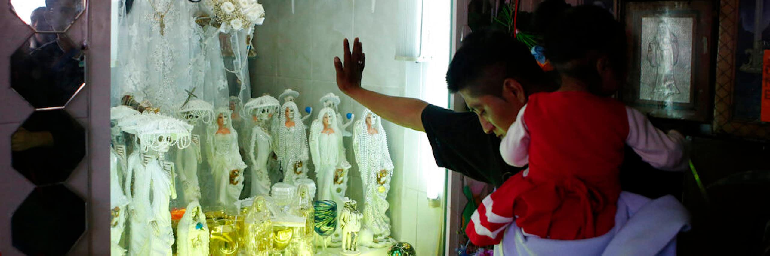 A man bows his head before a shrine.