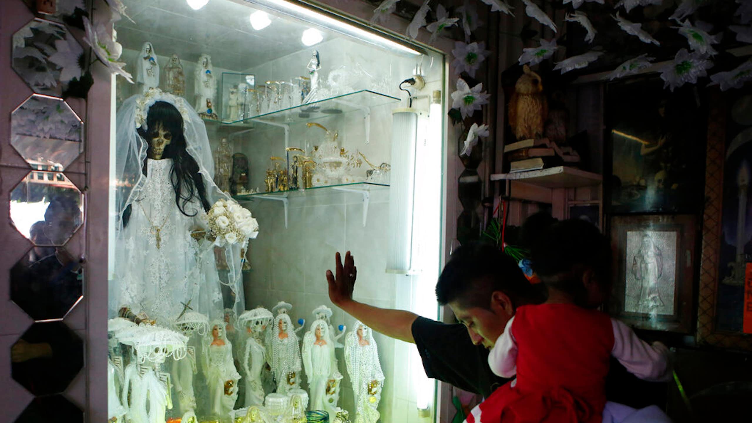 A man bows his head before a shrine.