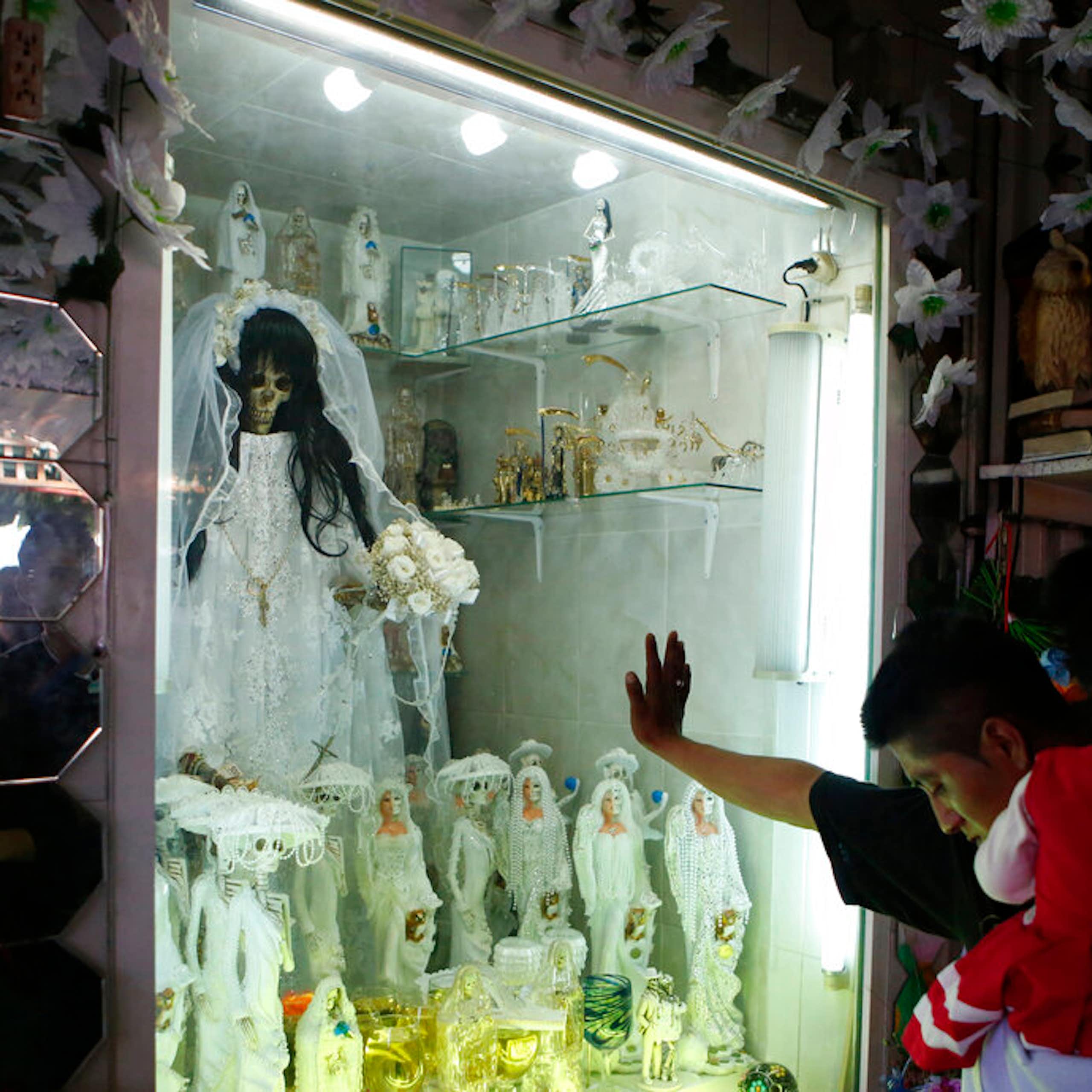 A man bows his head before a shrine.