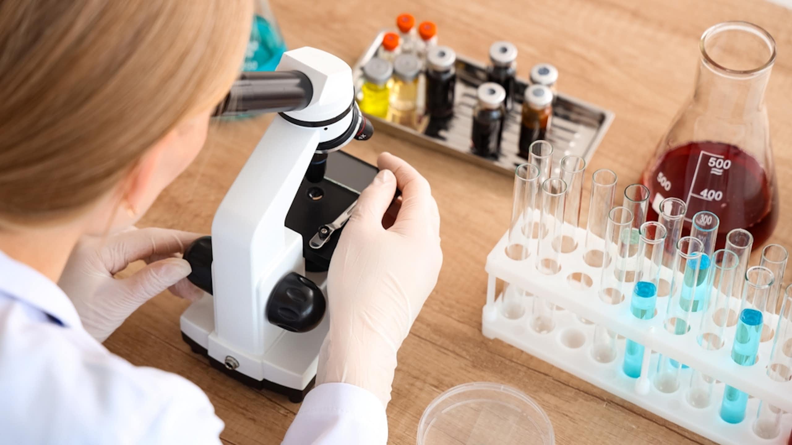 A woman works in a laboratory with a microscope.