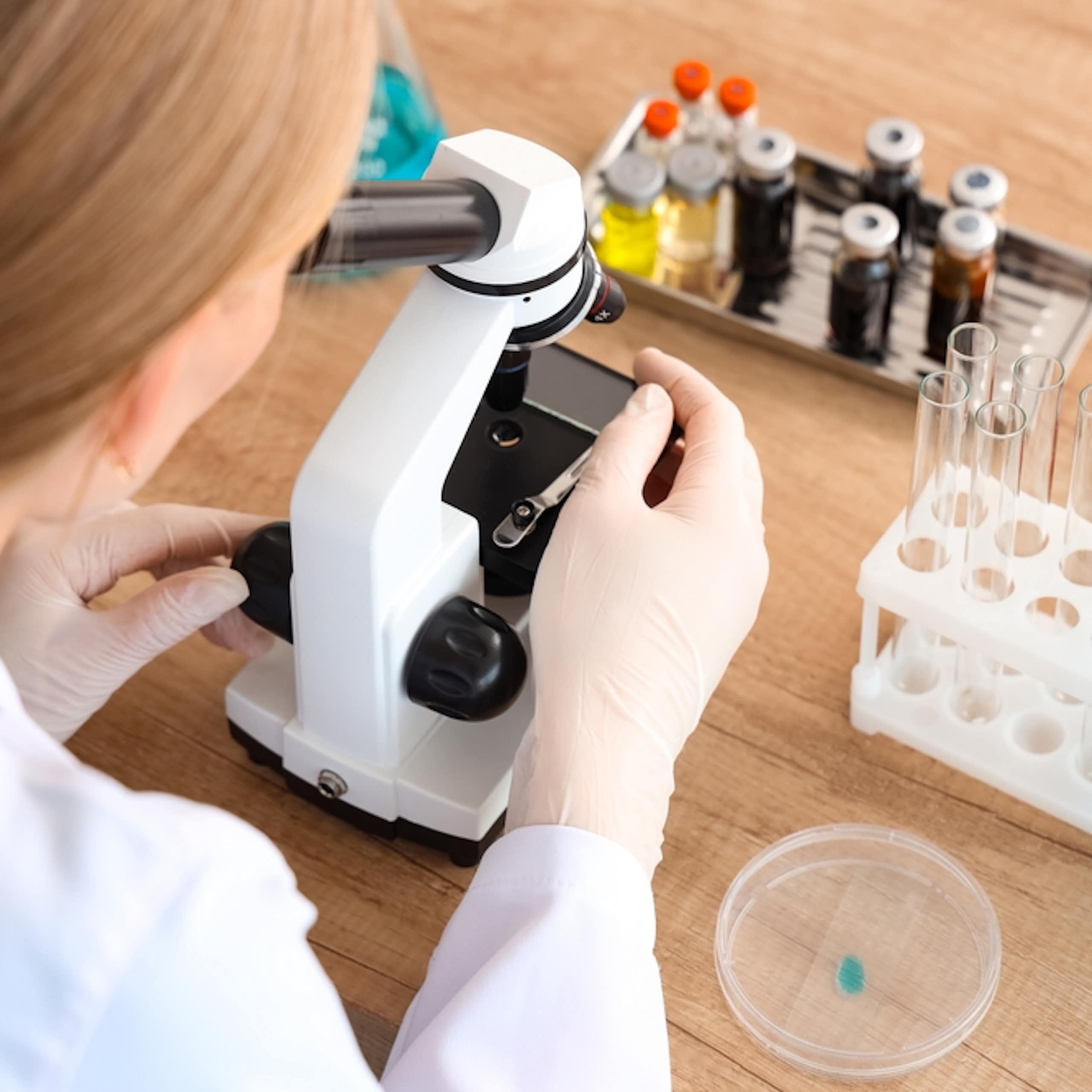 A woman works in a laboratory with a microscope.