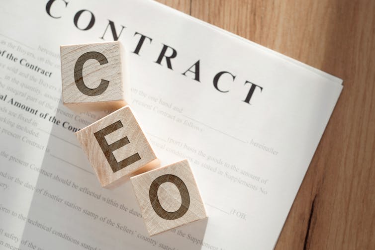 paper copy of an employment contract with wooden building blocks on top showing the letters c e o