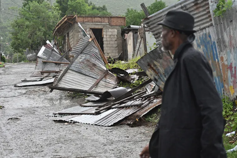Man looks at damaged buildings in Jamaica