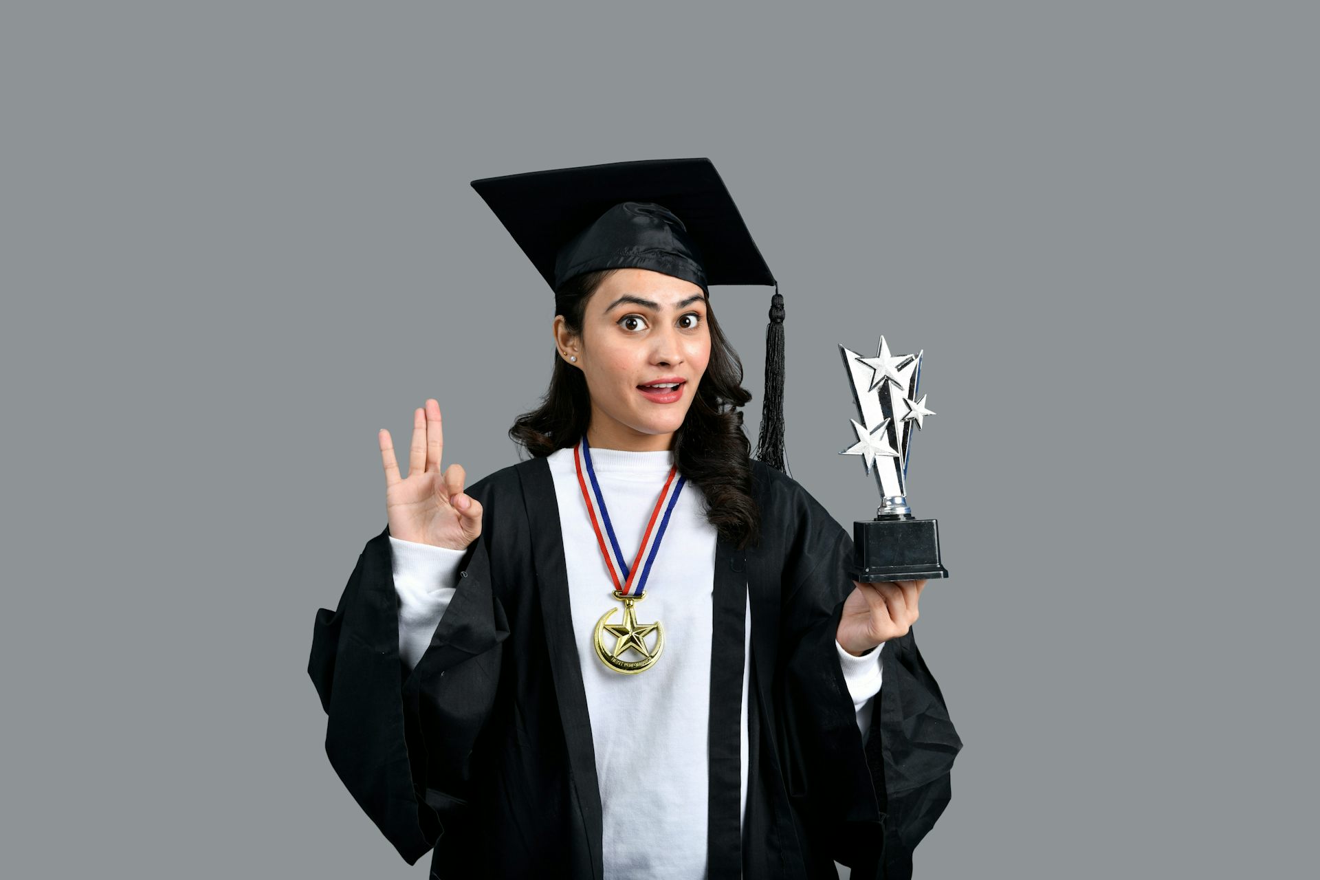 A graduate holding up a gold trophy.