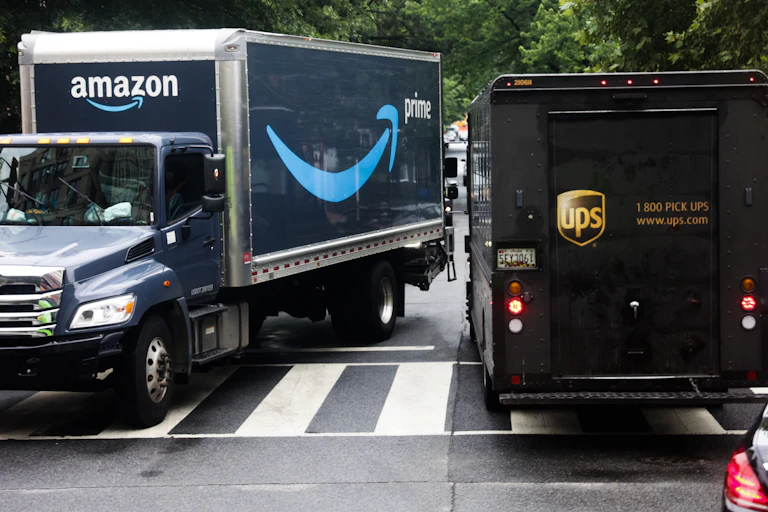 Amazon Prime and UPS trucks are seen on a street in Washington, D.C., on July 12, 2024. Both appear to be blocking the crosswalk.