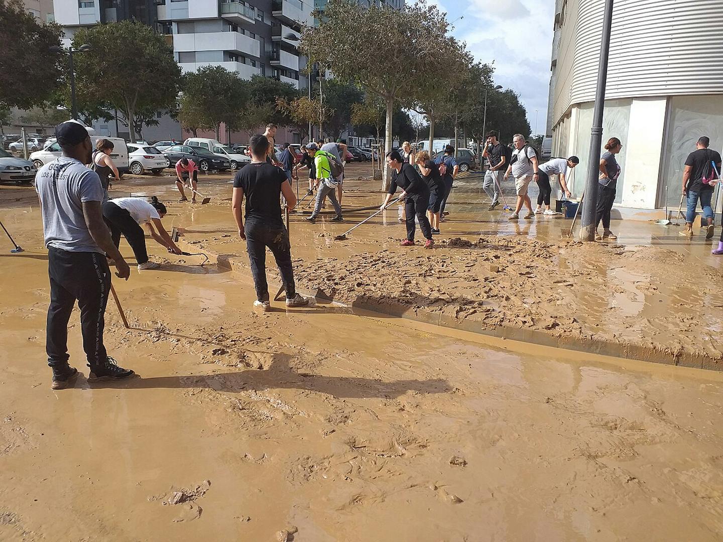 Personas limpiando el barro en una calle inundada