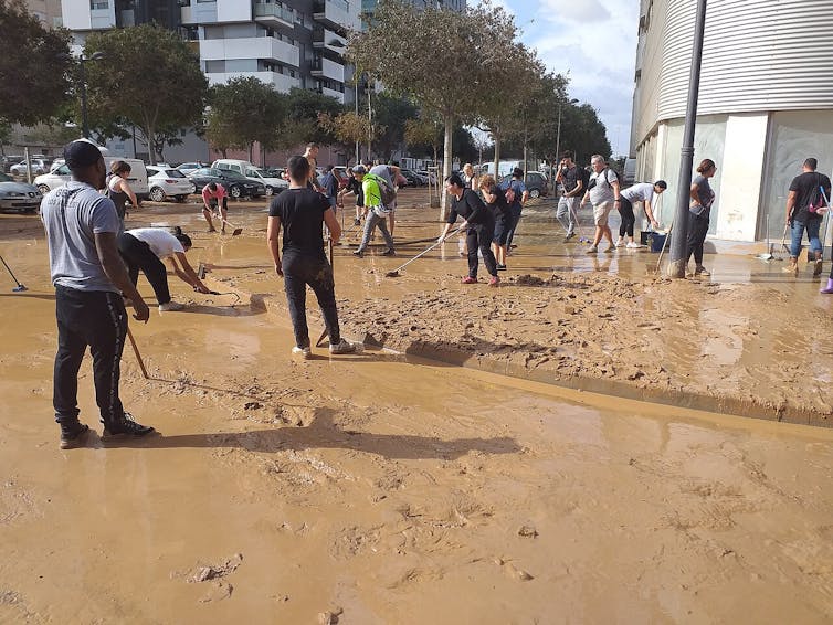 Personas limpiando el barro en una calle inundada
