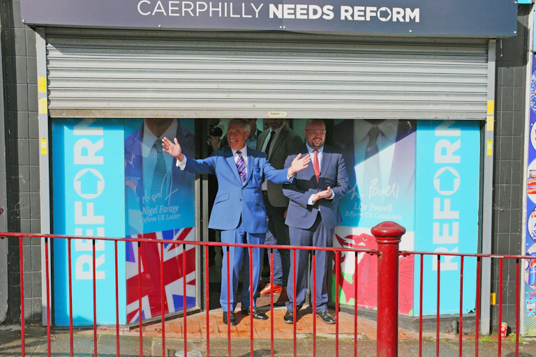 Nigel Farage and Llyr Powell posing in front of their Caerphilly campaign office.