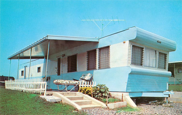 A robin-egg blue mobile home with fencing, a concrete front steps and a concrete front porch.