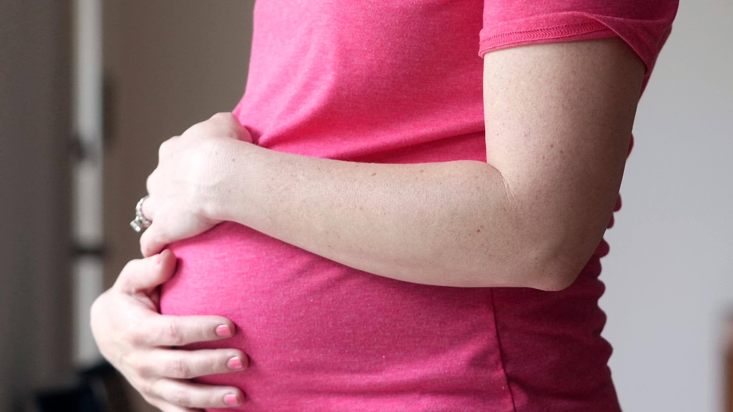 A pregnant woman is holding her belly