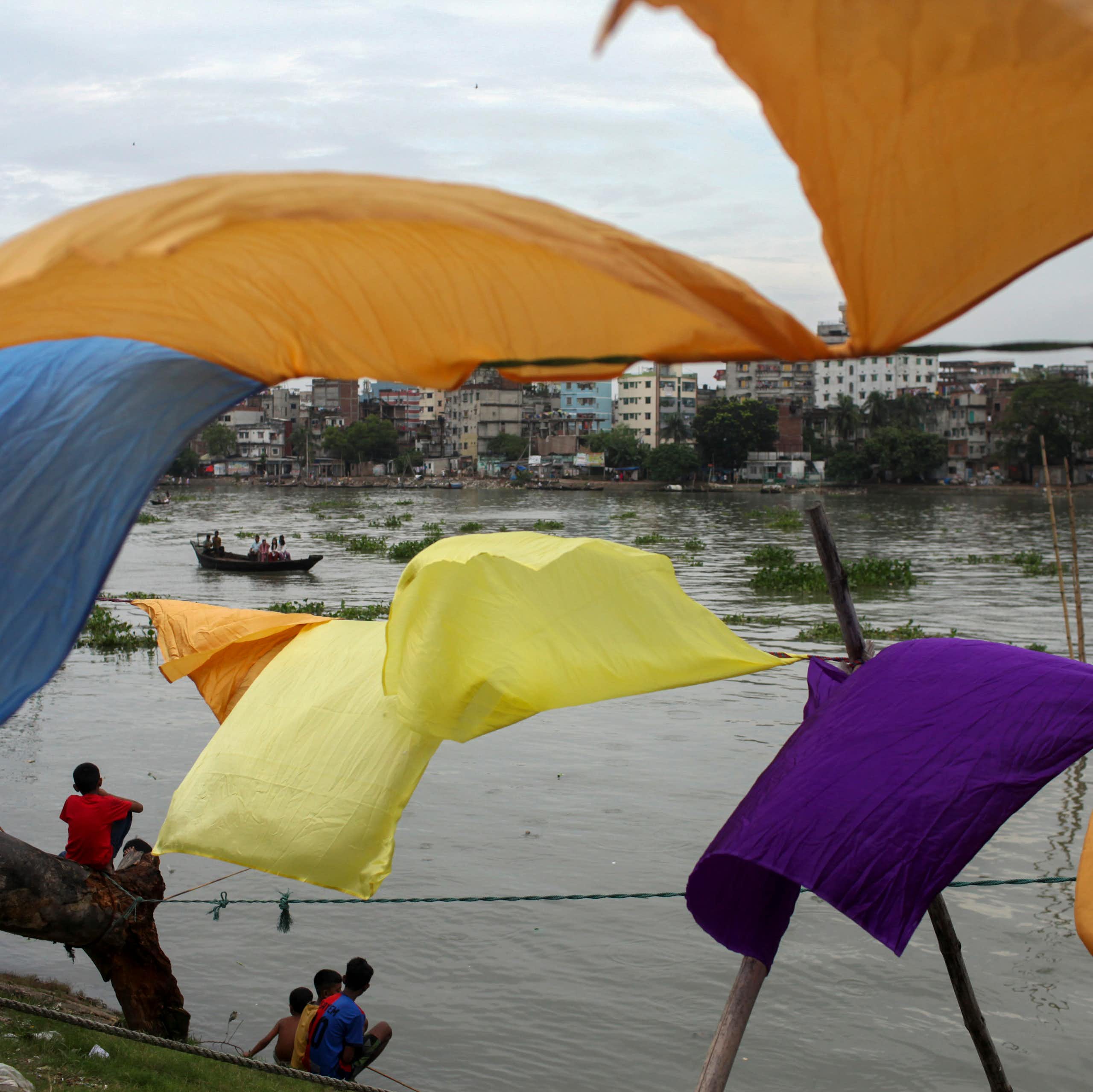 Colorful sheets fly on a line in front of a river.