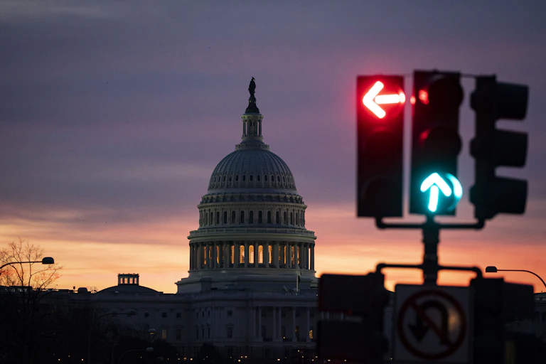 The US Capitol dome in the background with a traffic light signaling red on left, green on go straight.