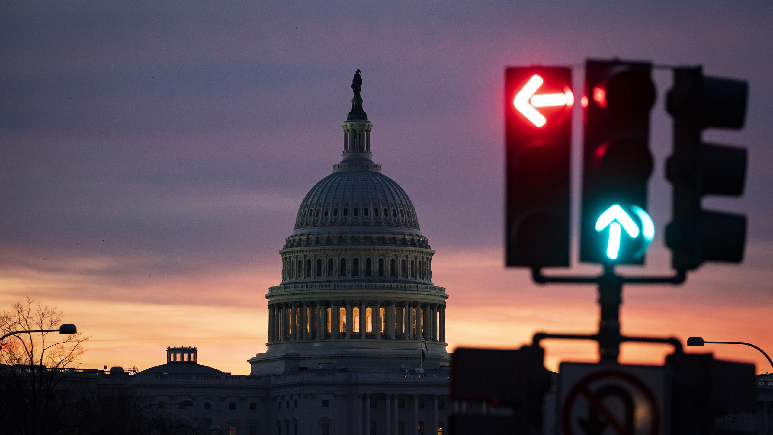 The US Capitol dome in the background with a traffic light signaling red on left, green on go straight.