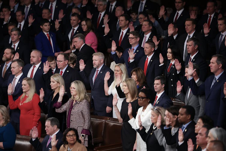 Many people standing and raising their hands to take an oath.