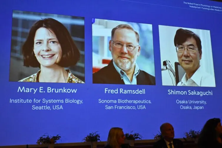 A screen showing the headshots of three researchers at a Nobel Prize announcement ceremony.