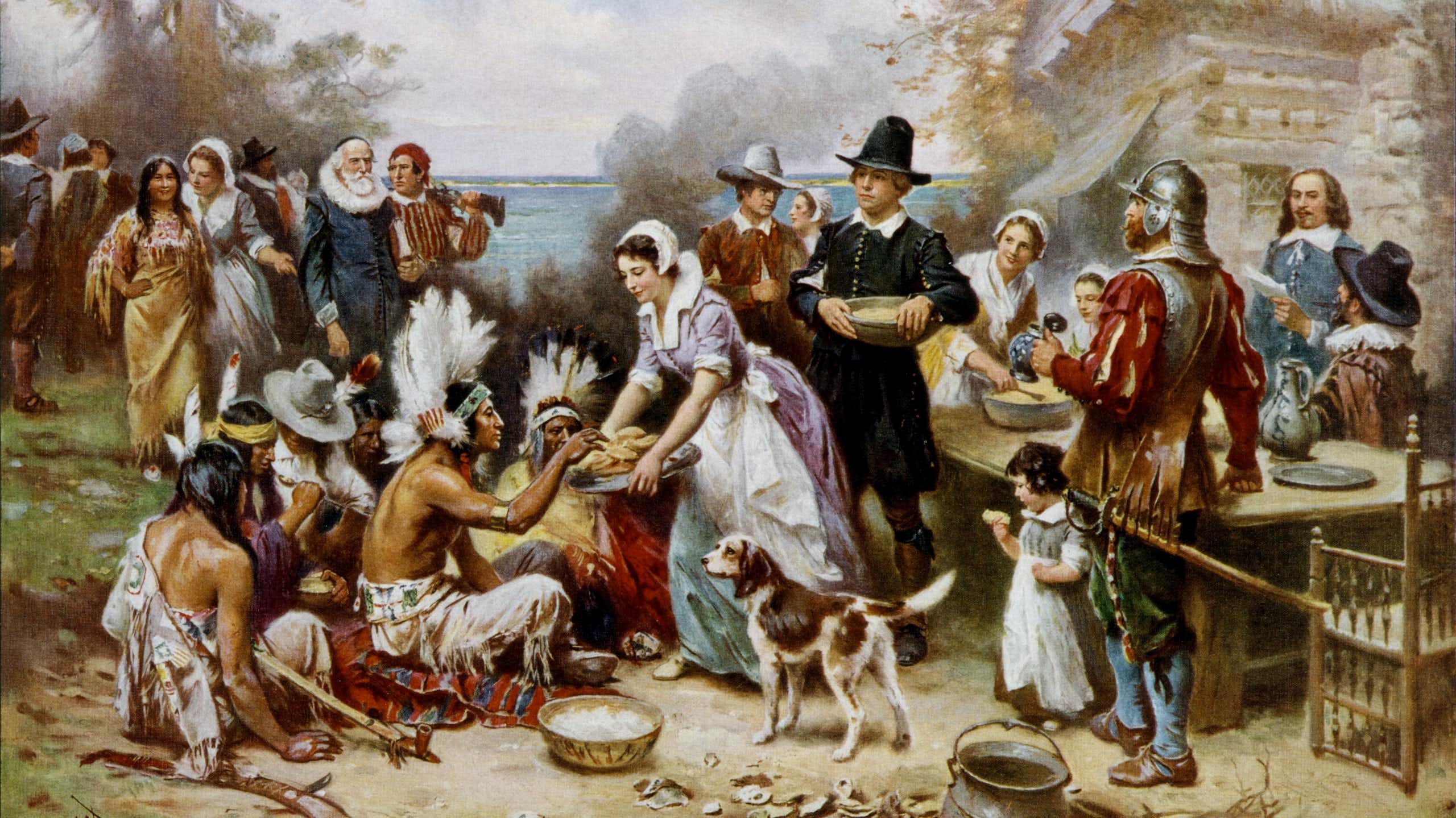 A painting shows Pilgrims and Native Americans chatting as they prepare a meal outside.