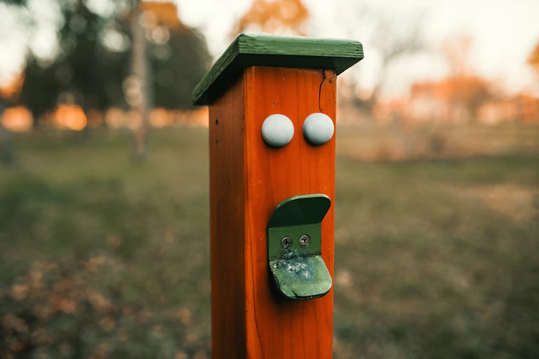 A red pole with two white dots above a piece of green metal.
