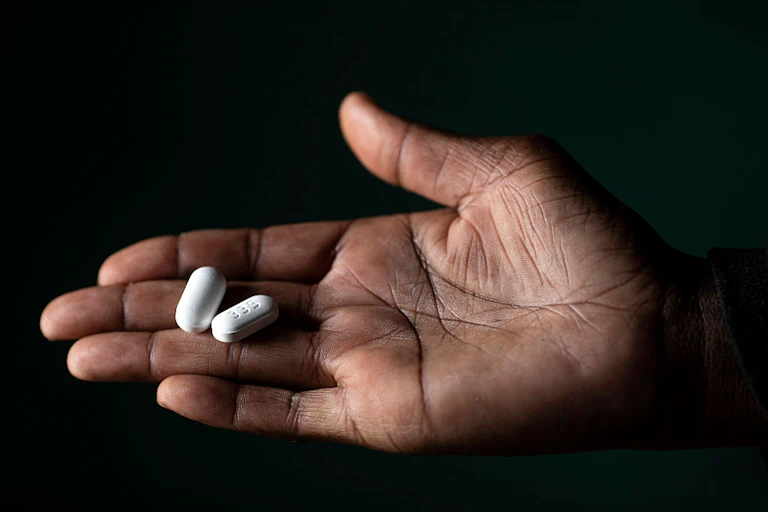 Hand holding two white pills