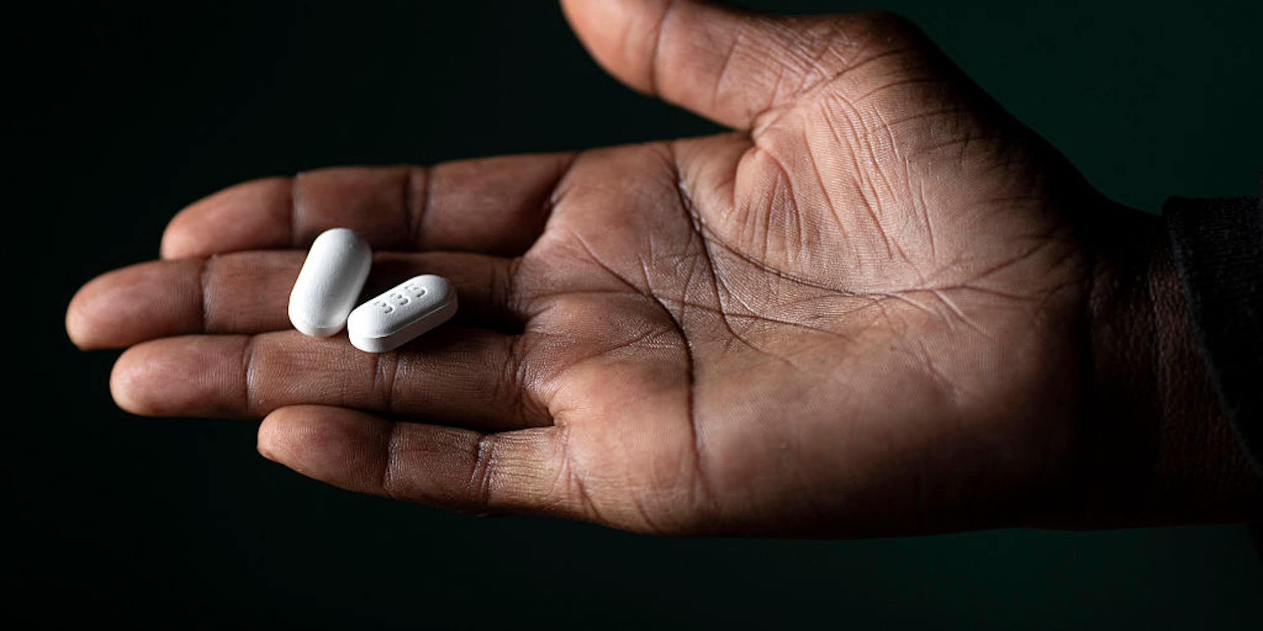 Hand holding two white pills