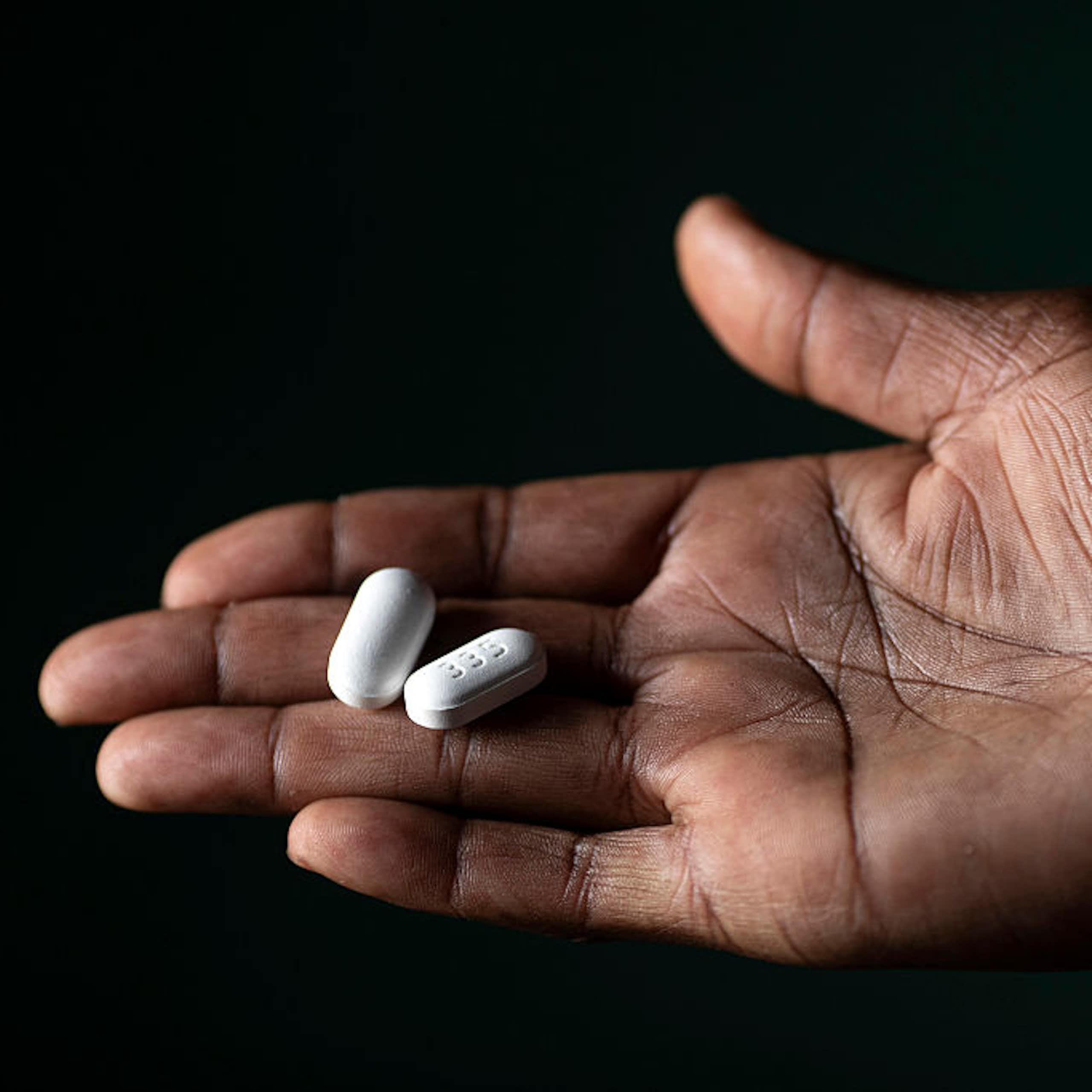 Hand holding two white pills