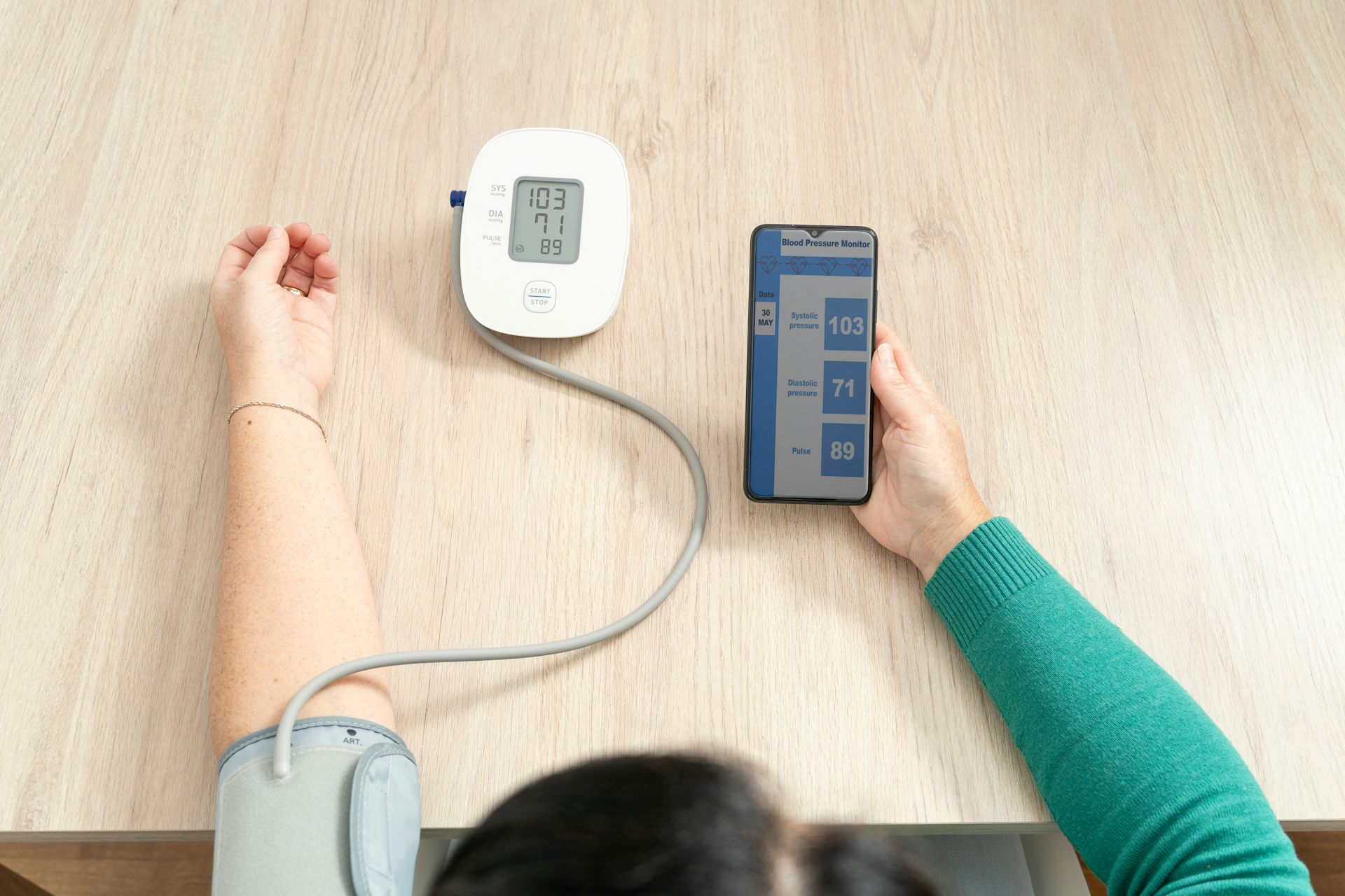 Una mujer se toma la tensión y consulta los resultados en el móvil.