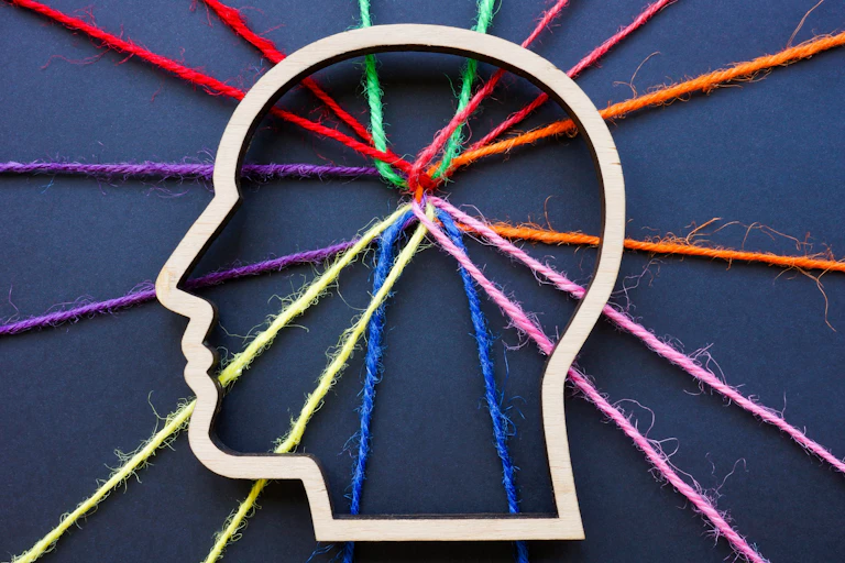 An outline of a human head with connected coloured threads criss-crossing
